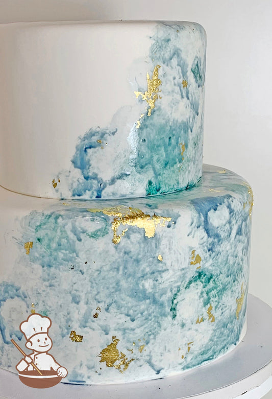 2 tier fondant wedding cake with water painted blue hues and finished with gold leaf accents.