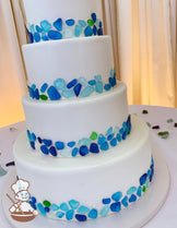 4-tier cake with blue shades of sea glass mosaic decorating the bottom portion of all cake tiers.