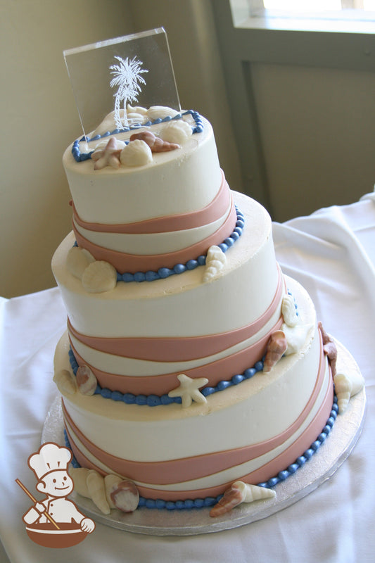 3-tier cake with peach and white fondant waves  with sea shells and blue beaded trim.