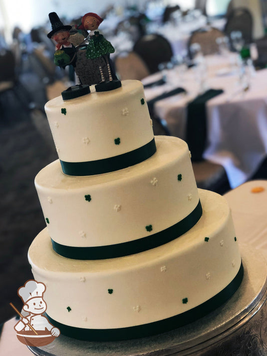 3-tier cake with green and white shamrocks hand piped, with dark green ribbon on base of all the cake tiers.