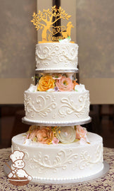 3-tier cake separated by white pillars and decorated with scrolls on the cakes and multi-colored sugar flowers in between the tiers.