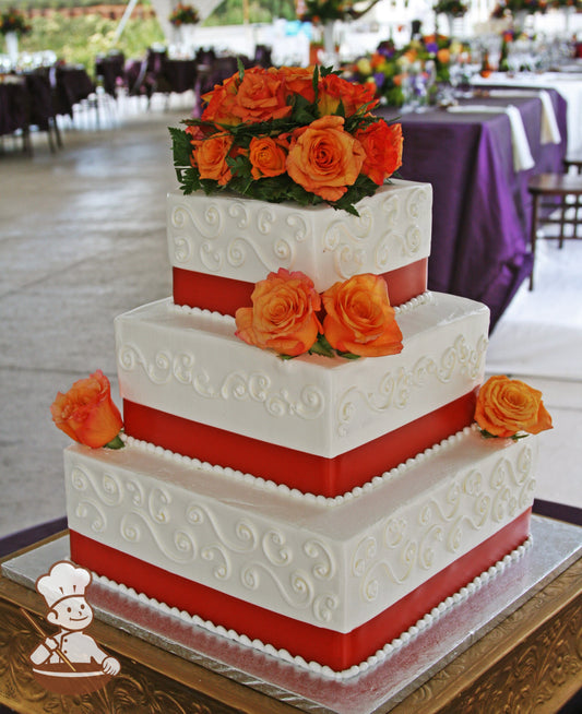 3-tier cake with smooth white icing and white scrolls, a red ribbon on the base of each tier and orange fresh flowers.