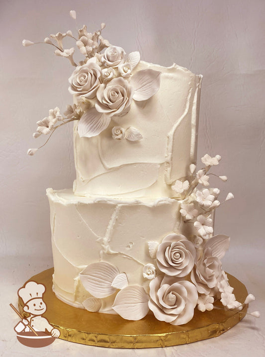 2-tier cake with lightly textured icing and an assortment of white sugar flowers & leaves.