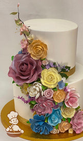 2-tier cake with smooth white icing and decorated with an assortment of colorful sugar flowers in pinks, oranges, yelllows and blues.