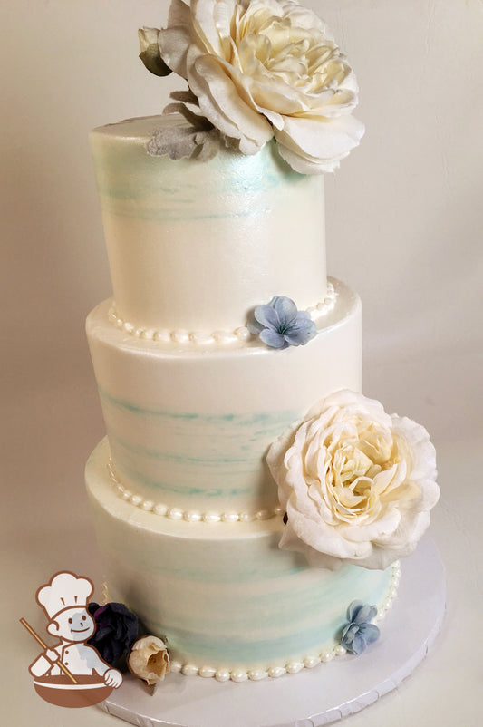 3 Tier Buttercream wedding cake with water color style icing and pearlescent shimmer sheen spray and large flowers.