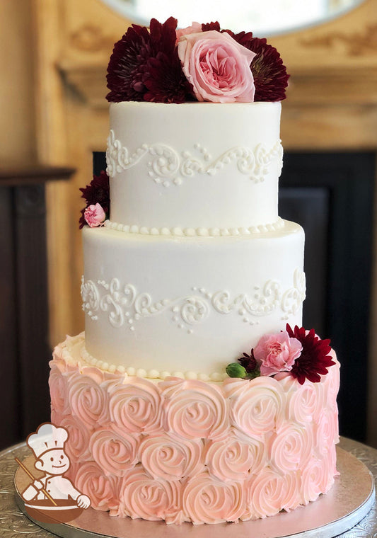 3 tier round buttercream wedding cake with coral rosette swirls bottom tier and smooth buttercream with elegant piping top tiers.