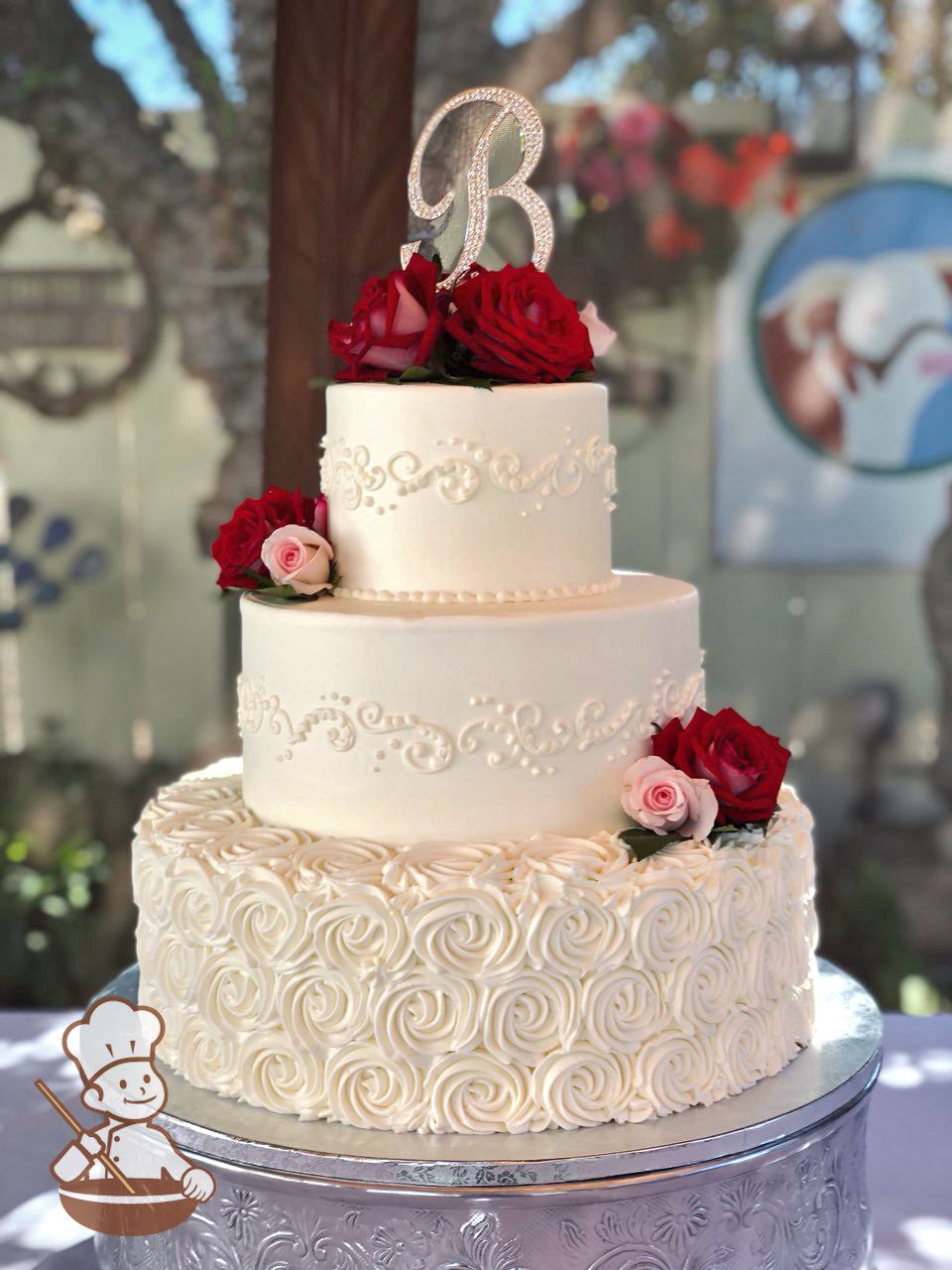 3 Tier round buttercream wedding cake with rosette swirl base and smooth white top tiers and elegant piping and decorated with fresh roses.