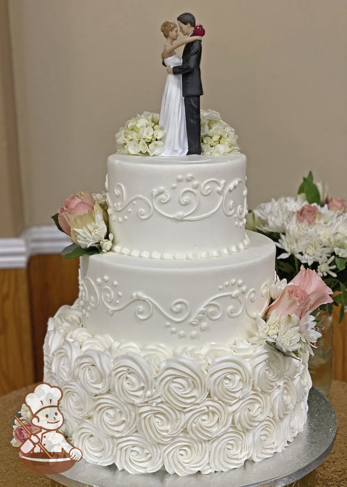 3 tier wedding cake with rosette swirls and elegant piping design finished with fresh flowers and traditional cake topper.
