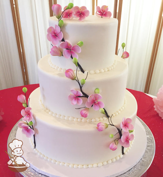 3 tier round smooth buttercream wedding cake with sugar cherry blossoms covering all 3 tiers and cake top.