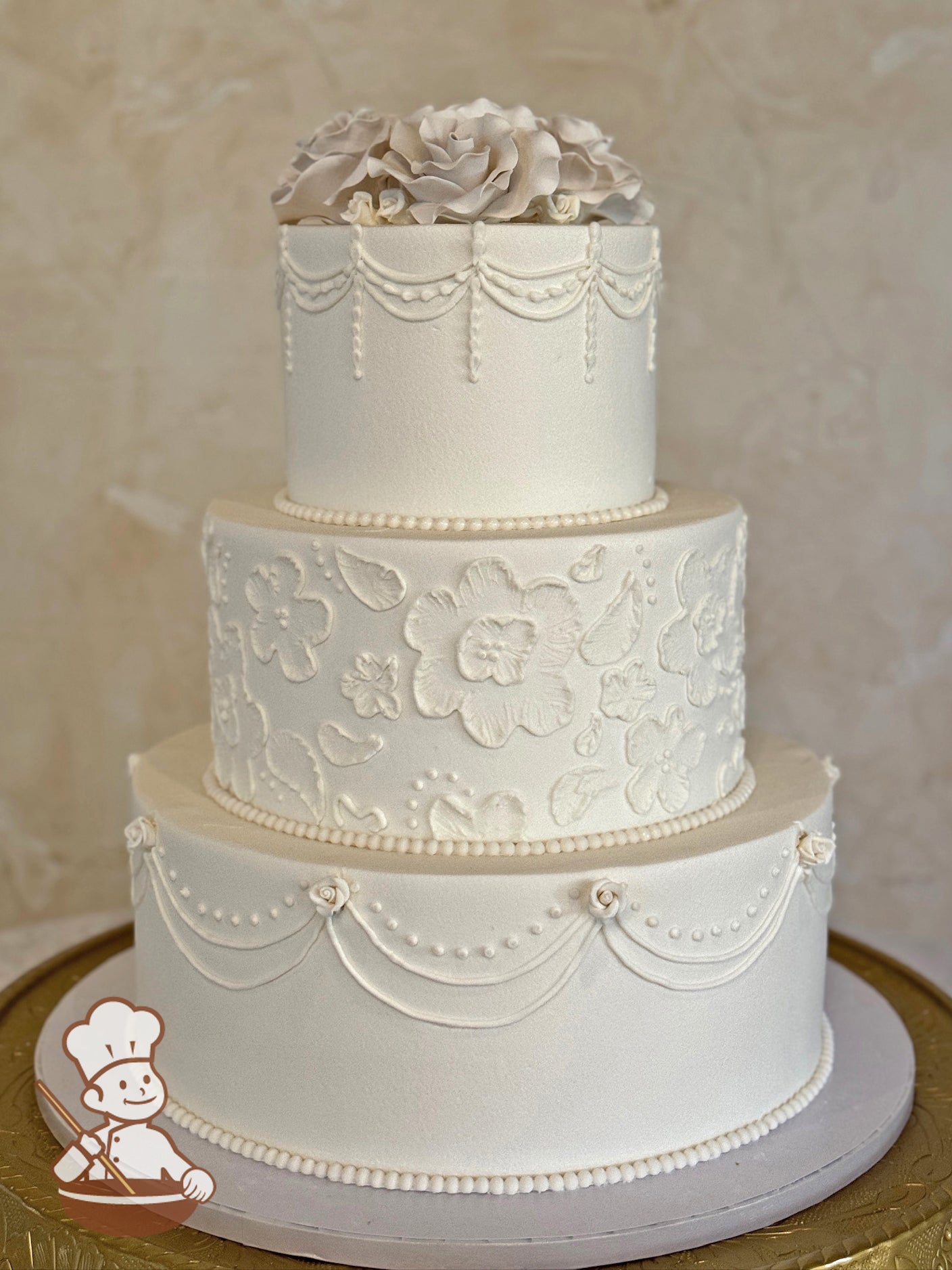 3 tier round wedding cake with brushed florals in middle tier and traditional piping on top & bottom tiers and finished with sugar flower topper.