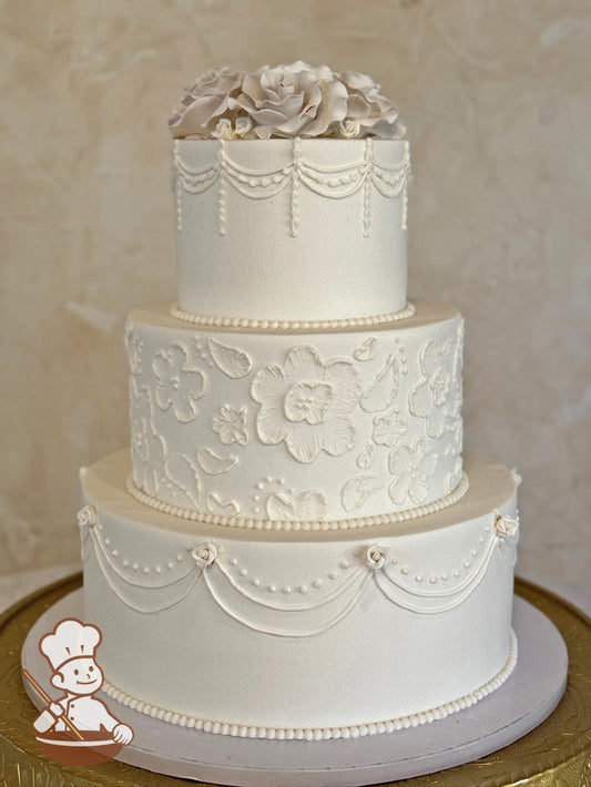 3 tier round wedding cake with brushed florals in middle tier and traditional piping on top & bottom tiers and finished with sugar flower topper.