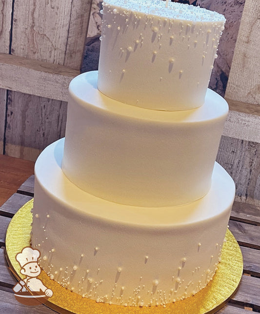 3 tier buttercream round wedding cake decorated with multi sized sugar pearl beads on top & bottom tier.