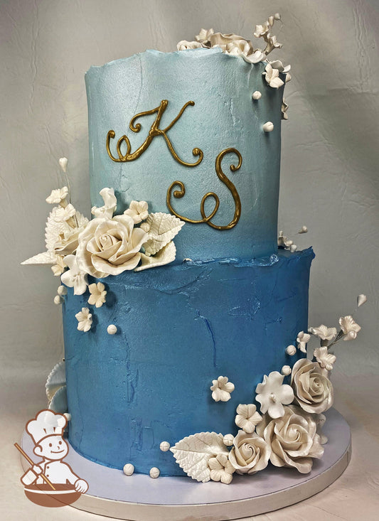 2 tier buttercream texture cake in blue tones and finished with pearlescent sugar flowers and pearl beads.