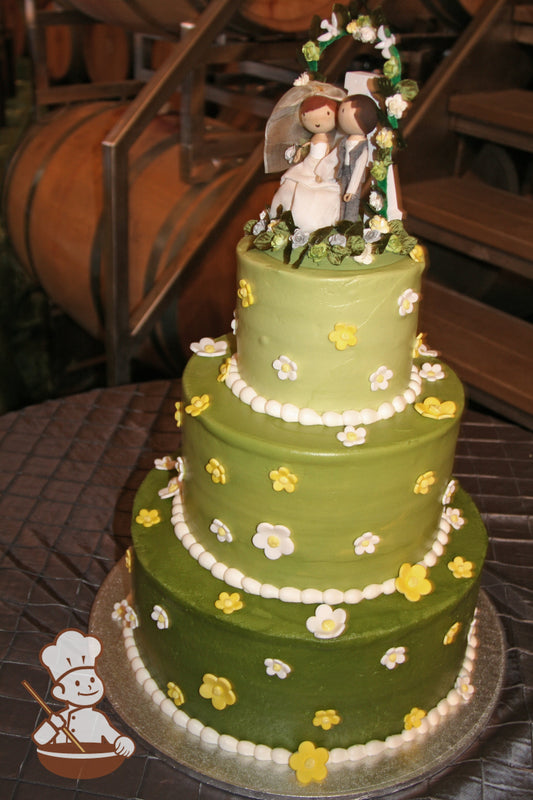 3 tier round cake with different green tones for meadow feel and finished with white and yellow fondant daisies.