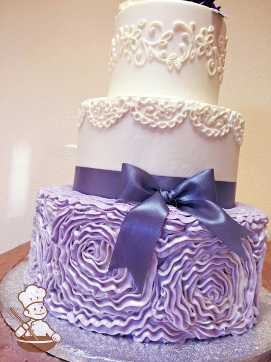 3 tier round wedding cake with large lavender floral swirls and traditional piping design.  Cake is finisehd with purple satin ribbon bow.