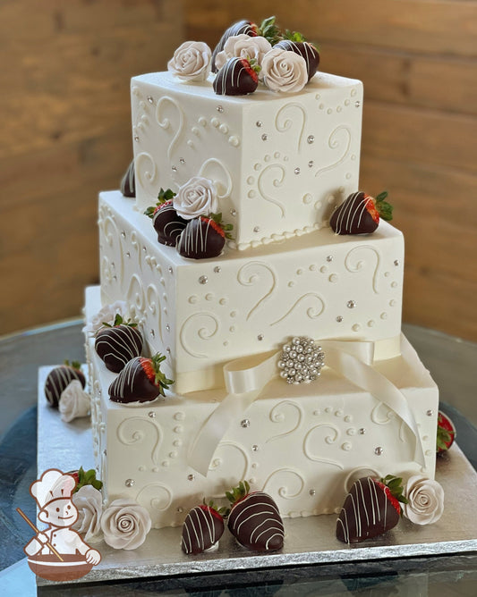 3 tier square offset wedding cake with chocolate dipped strawberries and sugar flowers.  Cake is finished with traditional piping and rhinestone.