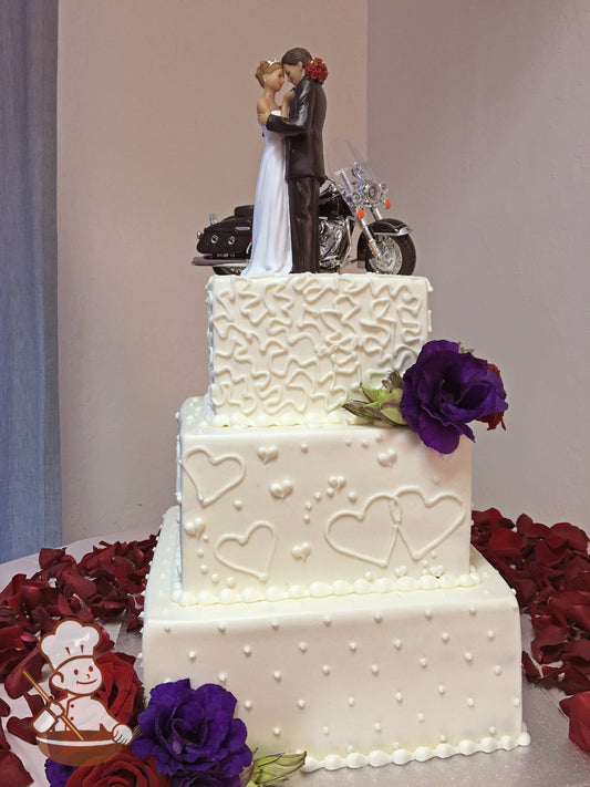 3 tier square cake with whimsical heart themed piping design and decorated with fresh flowers.
