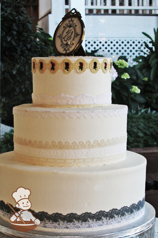 3 tier wedding cake with different fabric lace pattern designs in grays, white and cream wrapping all tiers of the cake.