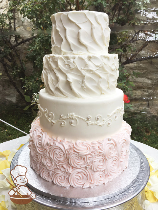 4-tier cake decorated with light-pink rosettes on the bottom tier, white scrolls and pearls on the second tier and texture on third and top tier.