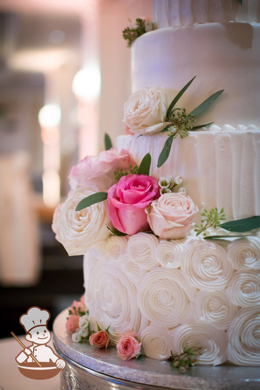4-tier cake decorated with white buttercream rosettes on the bottom tier and a thin vertical texture on the second and top tier.