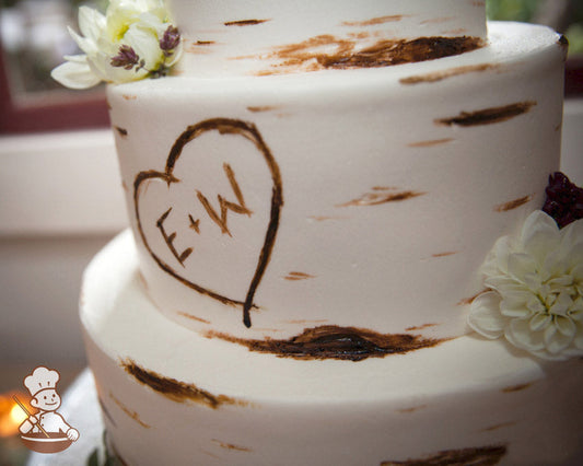 3-tier cake with smooth white icing and decorated with a painted wood grain look and a heart with the initials E + W.