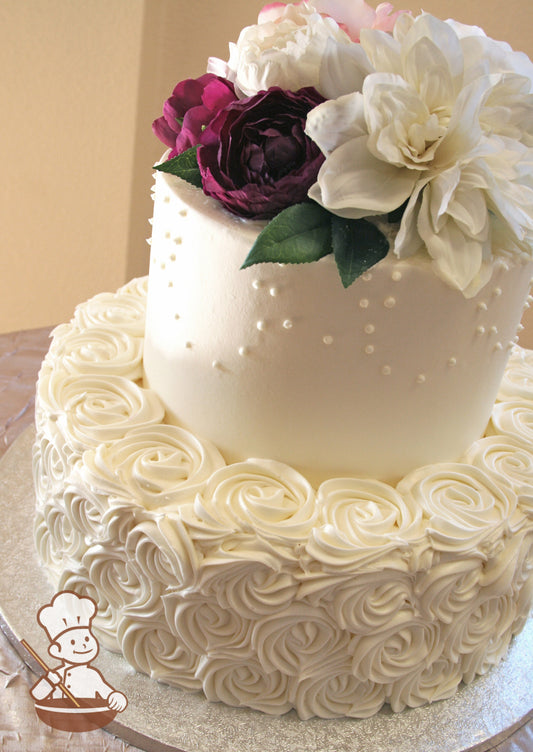 2-tier cake with white icing and decorated with buttercream rosette swirls on the bottom tier and buttercream dot loop piping on the top tier.