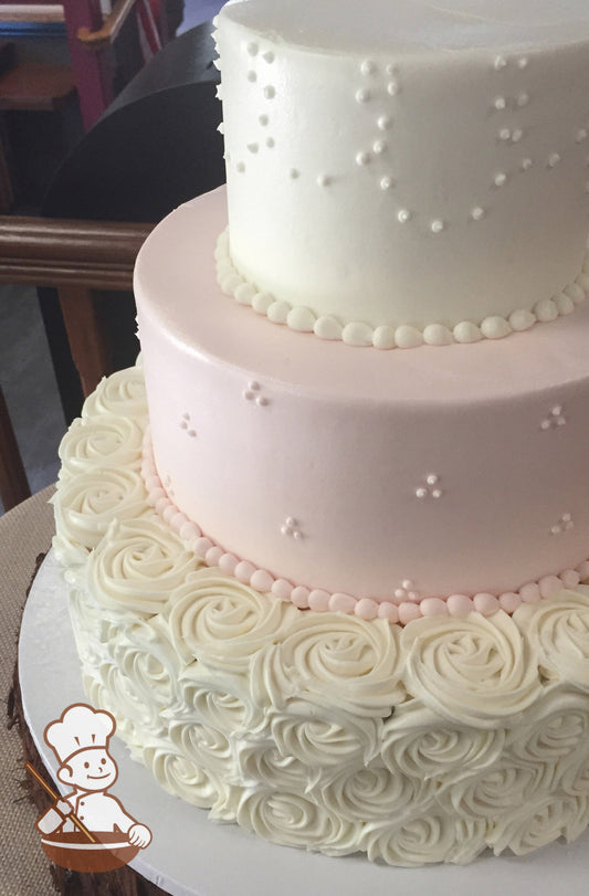3-tier cake decorated with white rosettes on the bottom tier, light-pink icing and tri-dot pipings in the middle tier and dot loop piping on top.