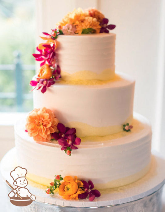 3-tier cake with white icing, decorated with a horizontal texture on the bottom and top tier and yellow sanding sugar on the base of each tier.
