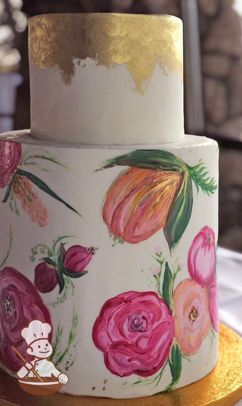 2 tier fondant wedding cake with floral water painting on bottom tier and gold leaf covered top tier.