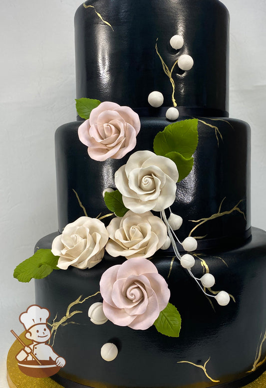 3 tier black fondant wedding cake with painted gold fault lines and decorated with light pink & cream sugar roses.