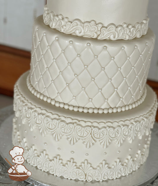 3 tier fondant wedding cake with vintage wall decor, quilted pattern with pearl beads and pearlescent shimmer spray for a timeless look.
