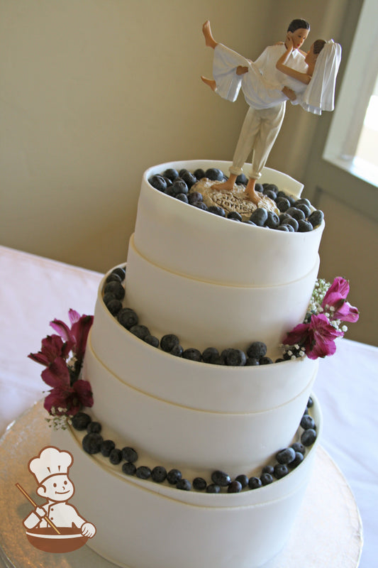 3 tier round fondant wedding cake with a rolling wrap and filled with fresh berries and fresh flowers.