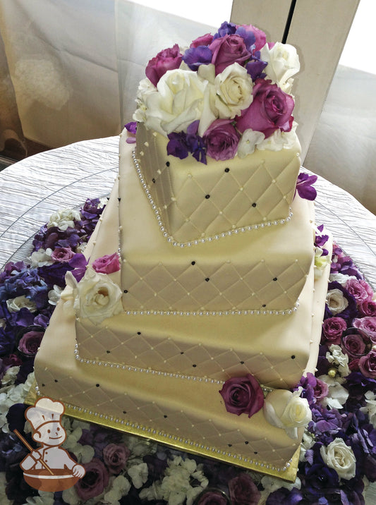 4 tier cream fondant cover with quilted pattern and beaded piping decorated with fresh flowers.