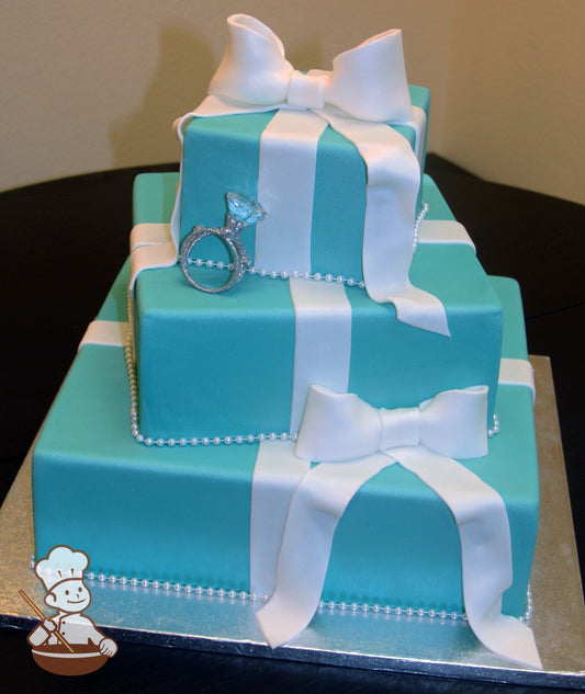 3 tier square offset tiffany blue gift box fondant cake with fondant white ribbon bands & bows and finished with a wedding ring set.