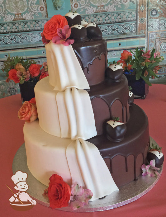 3 tier fondant white & chocolate fondant cake with chocolate ganache drip, white fondant drapes, tuxedo chocolate strawberries & fresh flowers.