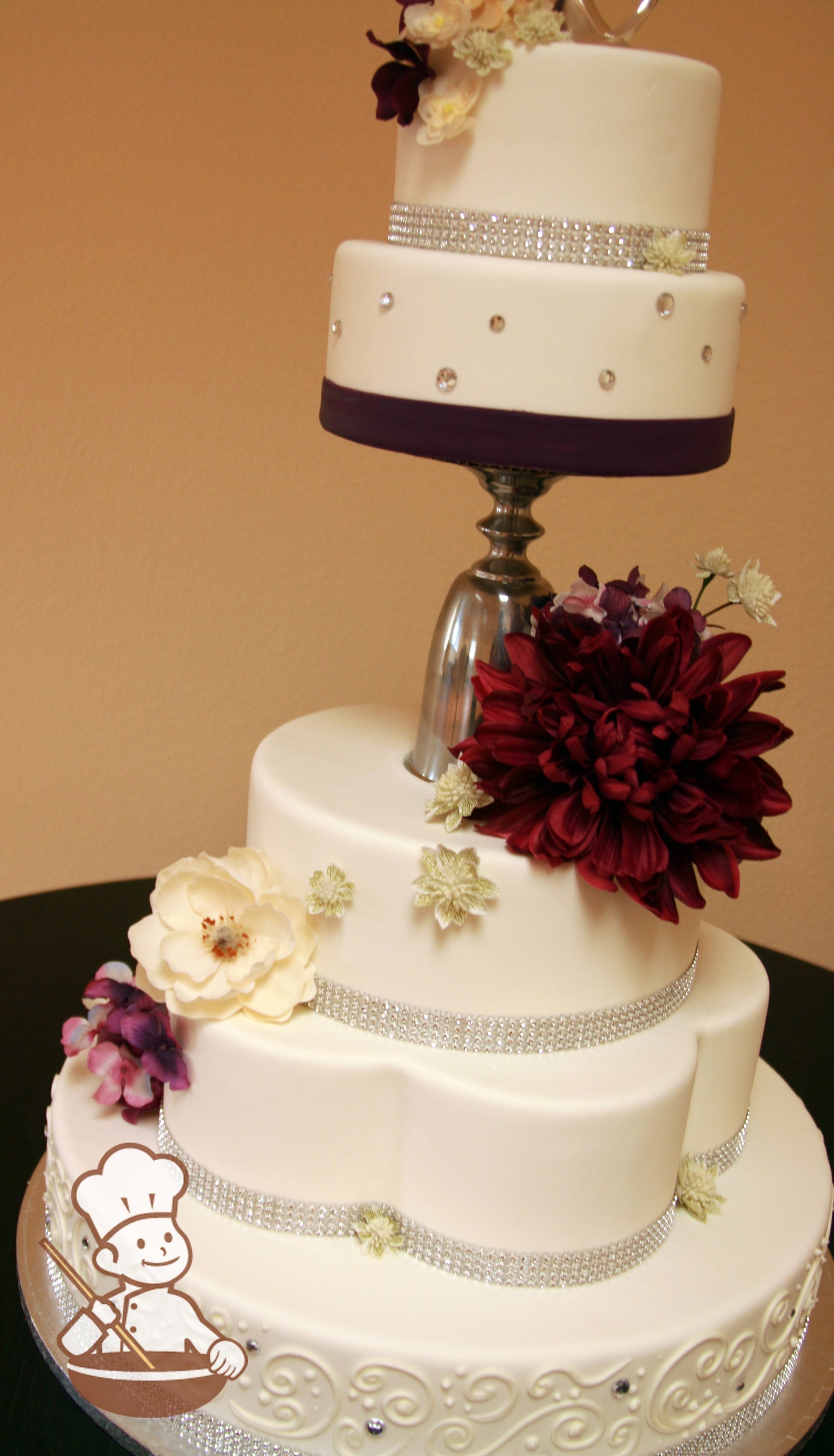 Round and daisy shaped fondant cake with a unique pestal separator and decorated with classic piping and rhinestone beads and bands.