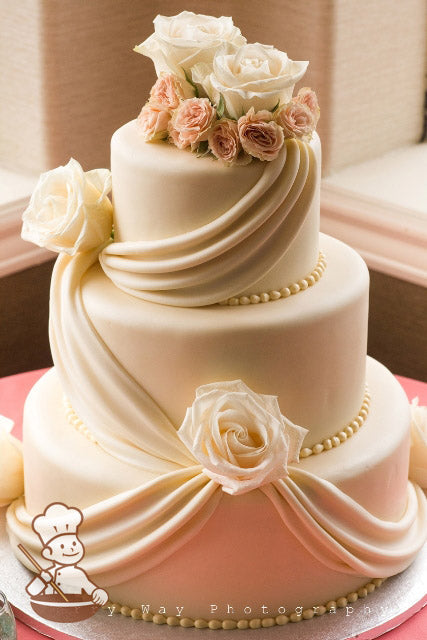 3 tier Ivory fondant wedding cake with single & double drape design and fresh flowers.