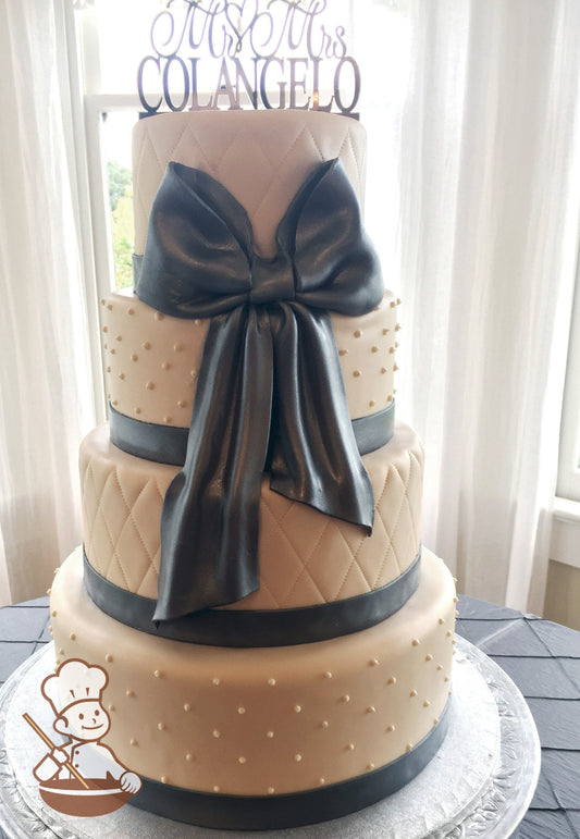4 tier fondant wedding cake with quilted pattern and bead piping decorated with a large gray/silver fondant bow.