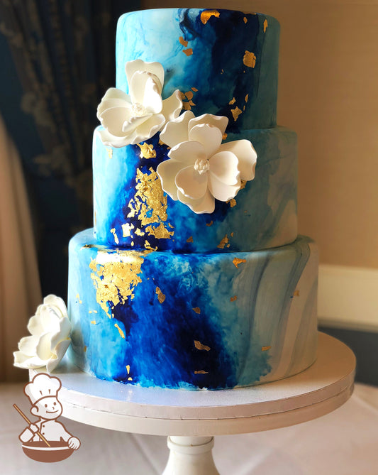 3 tier blue marble fondant wedding cake with painted darker blue center and gold leaf accents.
