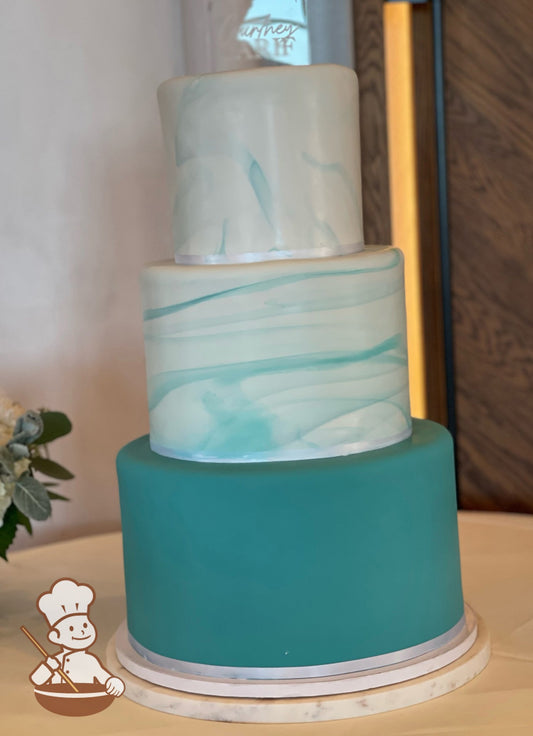 Teal colored fondant wedding cake with solid bottom cover and marble pattern covering top 2 tiers.