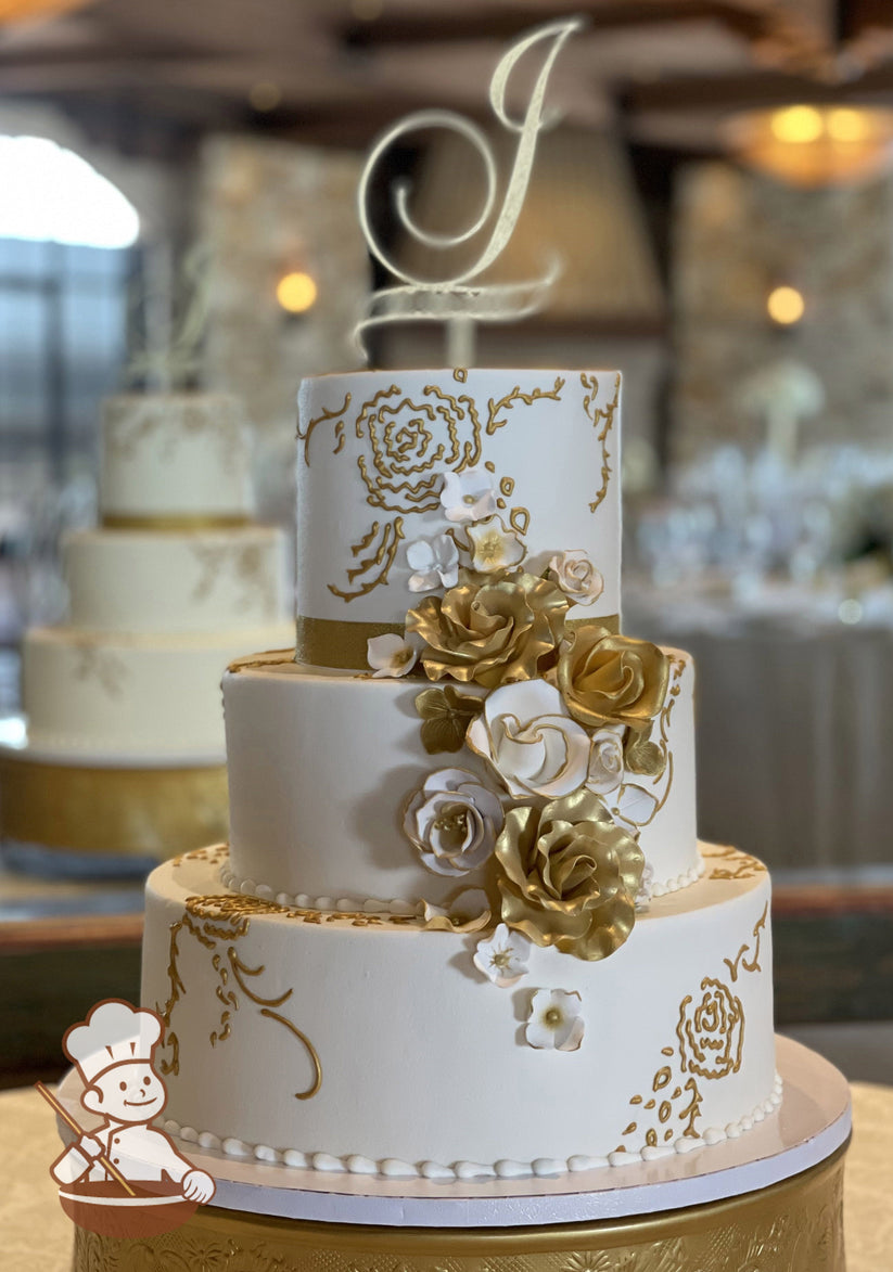 3-tier cake with smooth white icing and decorated with metallic gold pipings and sugar flowers in white and gold colors.
