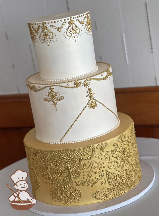 3-tier cake with a gold bottom tier and hand-piped metallic gold design and the top 2 tiers have smooth white icing with hand-piped gold detail.