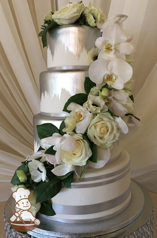 4-tier cake with white icing and decorated with silver paint on the top three tiers and silver ribbons on the bottom tier.