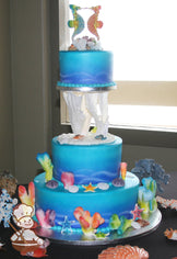 3-tier cake decorated with coloring to look like under the sea and colorful coral, seashells and sea animals.