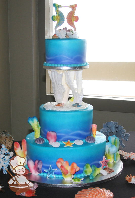 3-tier cake decorated with coloring to look like under the sea and colorful coral, seashells and sea animals.