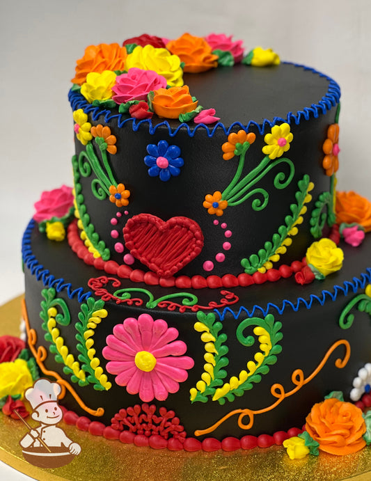 2-tier cake with black icing and decorated with buttercream piping's in bright pink, orange, red, yellow and green for a Mexican Fiesta theme.