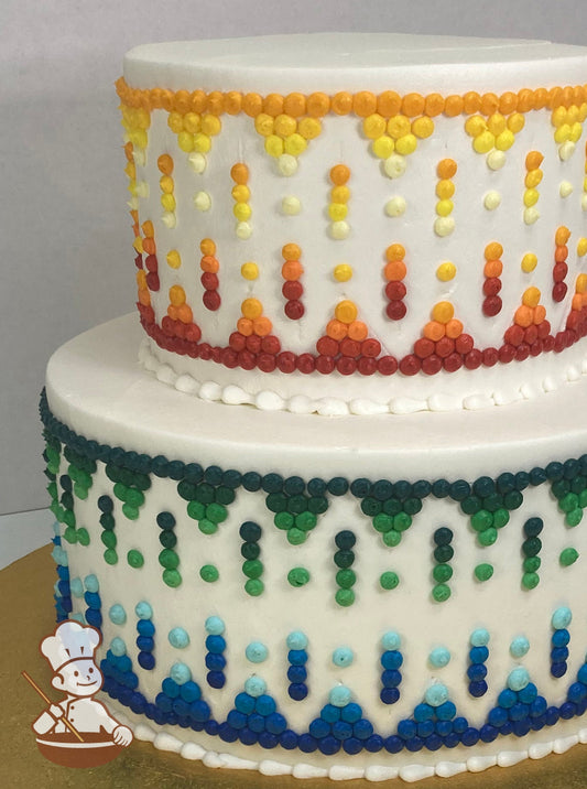 2-tier cake with bright colors in tribal band patterns. Top tier cake colors are red, orange, yellow and cream. Bottom is blue and green.