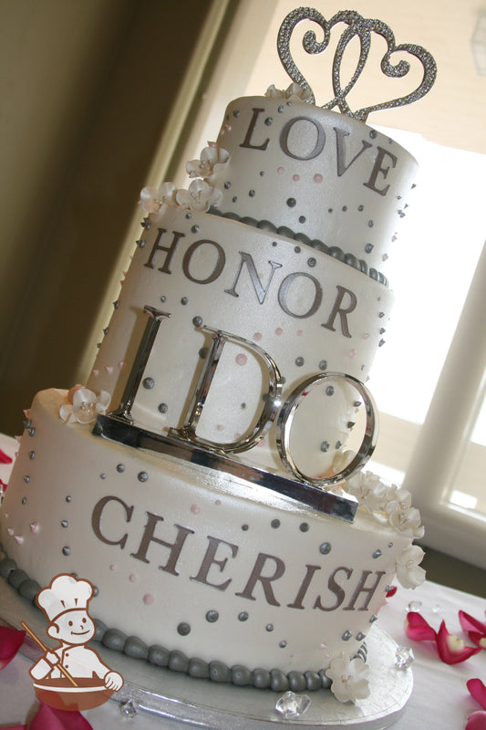 3-tier off-set cake with silver and pink dot patterns and shimmered. Fondant words on cake wall that say LOVE, HONOR, CHERISH.
