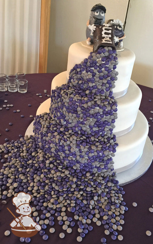 3-tier cake with silver ribbons. M&M characters pouring out a bag of M&Ms and waterfalling it down the cake.