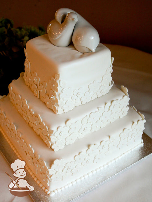 Square fondant wedding cake with fondant daisy covered walls and loving doves cake topper.